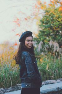 Portrait of smiling young woman standing against plants