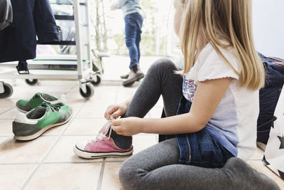 Girl wearing shoe while sitting on floor at day care center