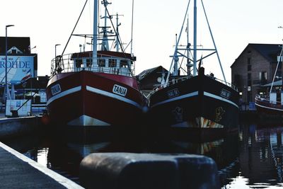 Boats moored at harbor against sky