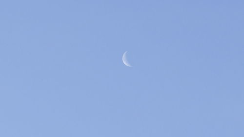 Low angle view of moon against clear blue sky