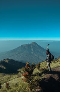 Man looking at mountain against blue sky