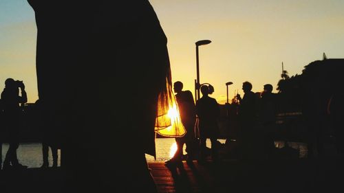 Silhouette men in city against sky during sunset