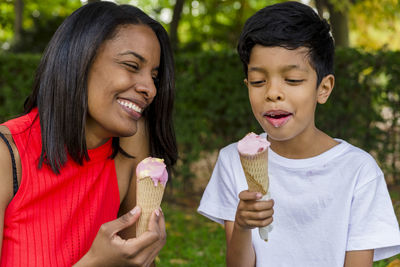 Mother and son enjoying eating ice-cream together outdoors in a park.