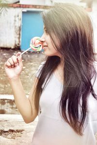 Woman holding candy while standing outdoors