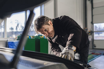 Male mechanic repairing car in auto repair shop