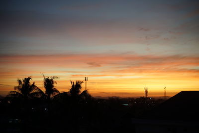 Silhouette trees and buildings against sky during sunset