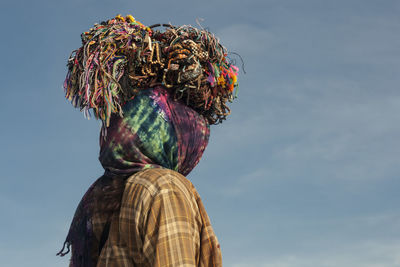 Woman carrying bracelets on head against sky