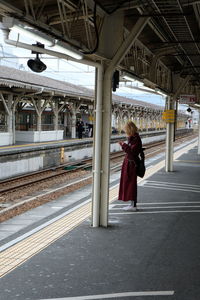 Rear view of woman standing at railroad station