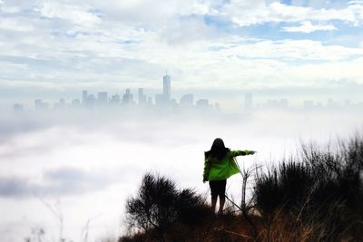 Rear view of man standing on city against sky