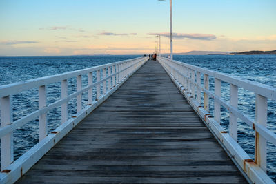 Pier over sea against sky during sunset