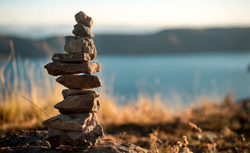 Stack of stones against lake during sunset