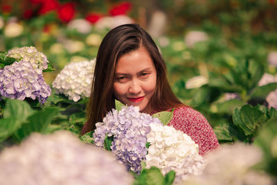 Portrait of smiling woman with flowers against blurred background