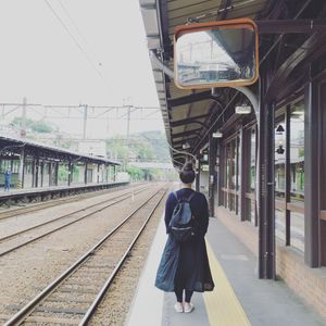Rear view of woman walking on railroad station platform