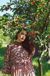 Woman standing by tree against plants