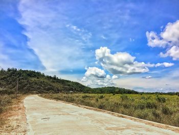 Road amidst field against sky