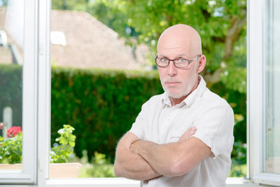 Portrait of man standing with arms crossed at home