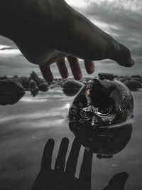 Close-up of hand holding water against sky