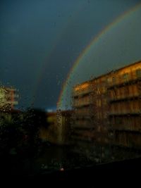 Rainbow over buildings seen through wet window