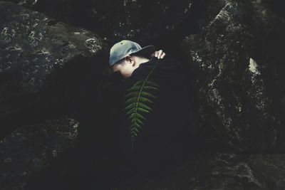 Side view of young woman standing by tree trunk