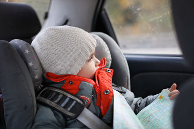 Boy looking though window while sitting in car