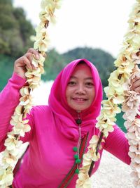 Portrait of a smiling woman holding pink flower
