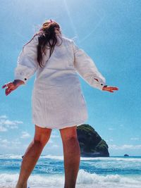 Rear view of woman standing at beach against sky