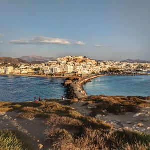 Scenic view of sea by townscape against sky