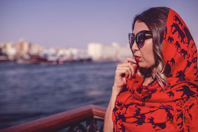 Close-up of young woman standing by railing against lake