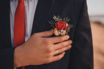 Midsection of bridegroom holding bouquet