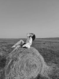 Rear view of woman sitting on field against clear sky