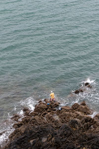 High angle view of man sitting on rock at beach