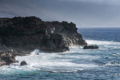 Rock formation on sea against sky