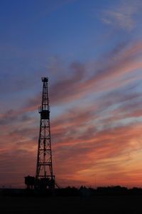 Low angle view of silhouette tower on field against sky during sunset