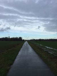 Road amidst field against sky