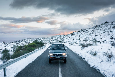 Car on road by snowcapped mountain against sky