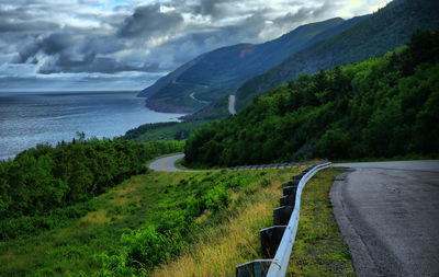 Scenic view of road by mountains against sky