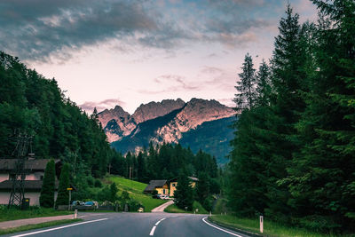 Road amidst trees and mountains against sky