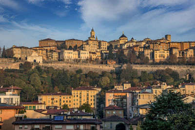 Buildings in town against cloudy sky