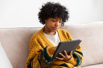 Young woman using laptop while sitting on sofa at home