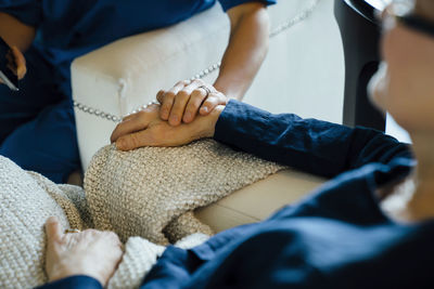 High angle cropped image of home caregiver consoling senior woman