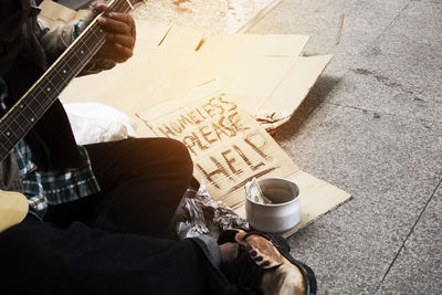 Low section of street musician playing music while begging on footpath