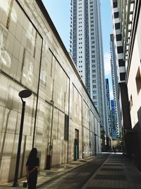 Street by modern buildings against sky in city