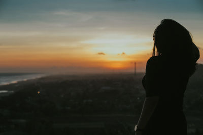 Silhouette woman standing against sky during sunset