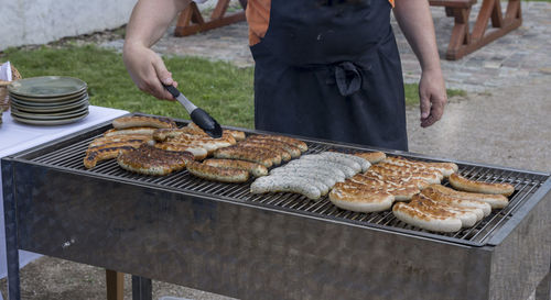 Midsection of man preparing food on barbecue grill