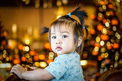 Portrait of cute girl looking away with curly hairstyle on gold bokeh light background. 