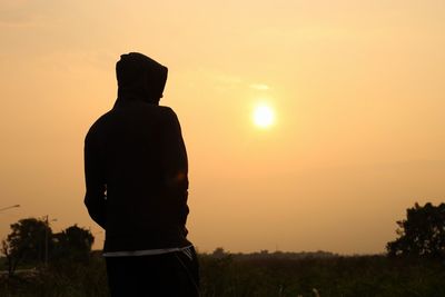 Silhouette man standing by tree against sky during sunset