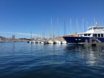 Boats moored at harbor against blue sky