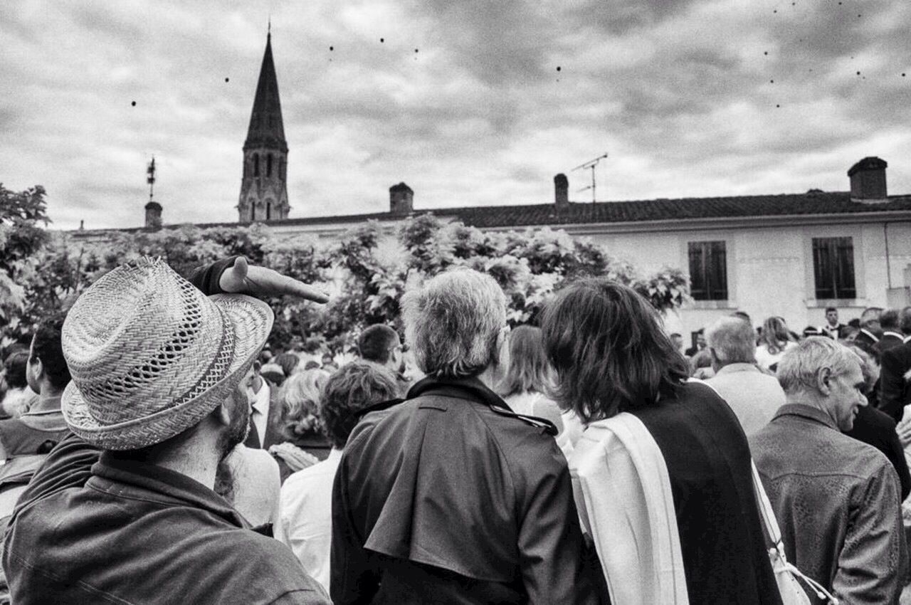 REAR VIEW OF PEOPLE IN FRONT OF BUILDING AGAINST SKY