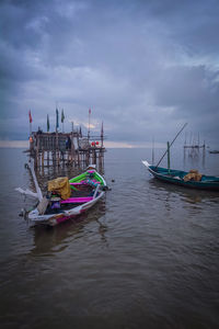 Fishing boats moored in sea against sky