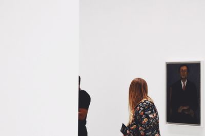 Rear view of woman standing against white wall